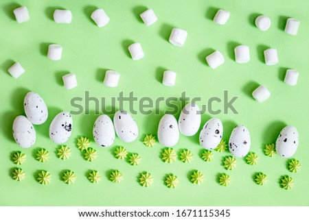 White easter egg on green paper pastel color background.Easter horizontal pattern.Holiday card with quail eggs. Sweet green candy.