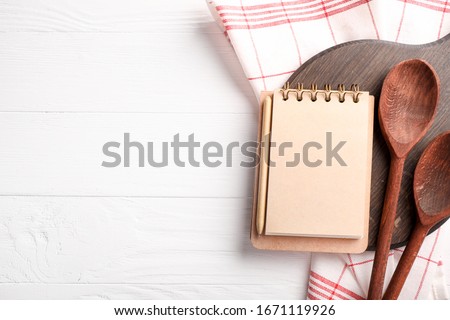 Recipe book, wooden spoons and board on white wooden background Royalty-Free Stock Photo #1671119926