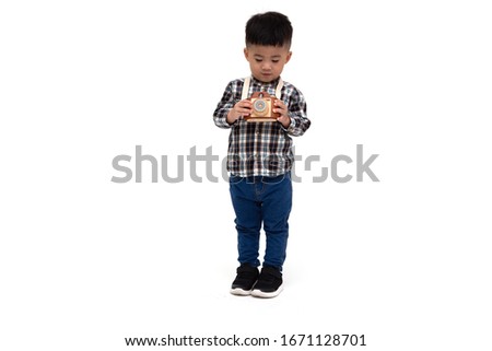 Attractive Asian little boy photographer wearing striped shirt standing isolated over white background, Taking a picture with toy photo camera, Two year one month old