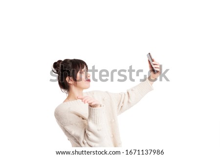Female make a selfie and showing i don't know sign with right hand and holding a cellphone in left. Isolated on white background.