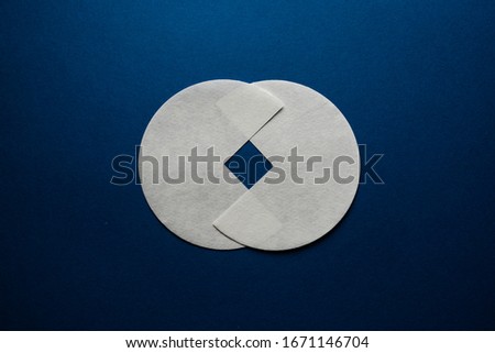 two gray paper circles are cut into one quarter on a dark blue background.