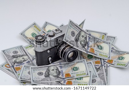 Vintage film camera on scattered American dollars. Concept of earning on photo stocks.