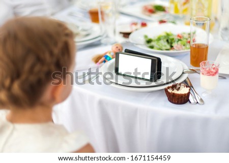Little girl is having meal while watching the movie on the tablet. Kid using smartphone, watching cartoons, addicted game and cartoon