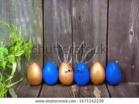 Happy Easter greeting card.Blue and gold eggs with cute Bunny ears on a rustic wooden background.Festive decoration.Spring holiday. Banner, Billboard for sale in the store, website.copy space.