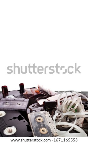 Vintage film camera rolls, old audio and video casettes with tape and foto strips isolated on a white background.