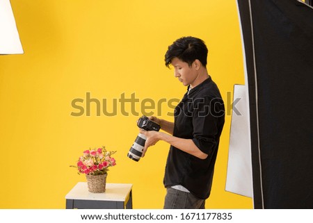 Portrait of young Asian male professional photographer is holding, checking the image on the camera and thinking while working in studio photo