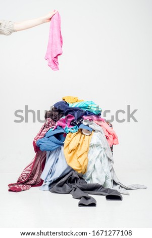 hand throws clothes into a pile with used clothes. Pile of used clothes on a light background. Second hand for recycling Royalty-Free Stock Photo #1671277108