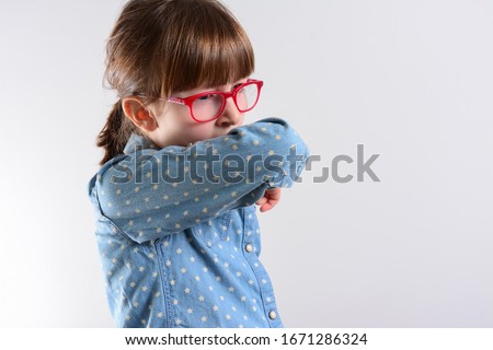 Unhappy kid Cough into her elbow, not her hand. Small girl pull the collar of her T-shirt up to cover mouth when coughing. Coughing advice from experts who seek to minimize risk of viral transmission Royalty-Free Stock Photo #1671286324