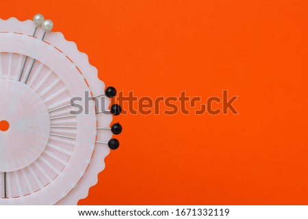 Needles in a round case on an orange background with place for text.