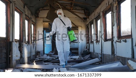 Disinfection against virus. Doctor virologist in protective suit sprays medicine, disinfect walls. Quarantine, epidemic. Global biohazard. Royalty-Free Stock Photo #1671337399