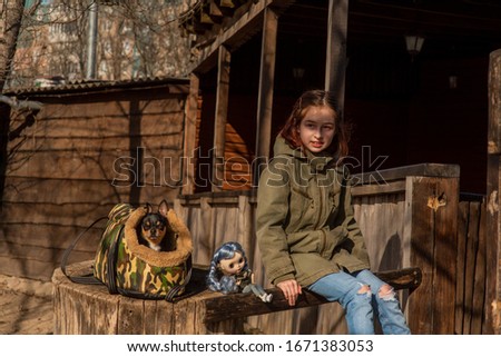 girl with a small dog. girl on a walk with a dog and a doll. Teenager, child, chihuahua. Dog in a bag for dogs. The hostess and her pet for a walk. Girl playing doll. Portrait of a girl 9 years old