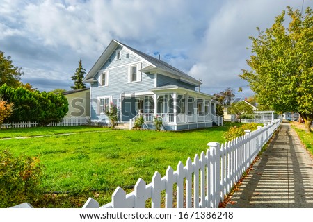A Victorian cottage with a white picket fence and covered front porch and deck in the Spokane, Washington area of the Inland Northwest, USA. Royalty-Free Stock Photo #1671386248
