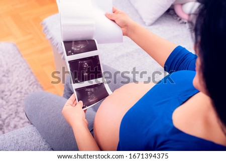 Pregnant woman looking at the ultrasound print of her unborn baby. 