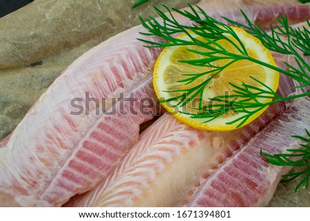 fish fillets of dogfish with lemon herbs on black background Royalty-Free Stock Photo #1671394801