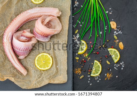 fish fillets of dogfish with lemon herbs on black background Royalty-Free Stock Photo #1671394807