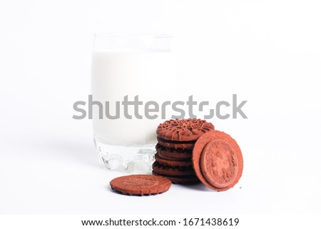 A picture of homemade chocolate cream biscuits with a glass of milk.