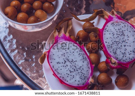  Pitahaya or dragon fruit and longan on plate. Tropical fruit on the table