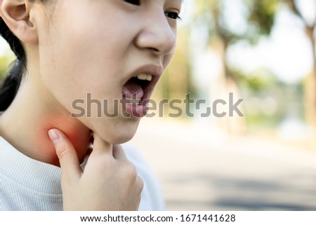 Sick asian child girl has sore throat,cough,hoarseness,laryngeal cancer,hand touch her neck,woman with throat problem,tonsillitis, loss of voice,infection of flu,colds,viruses,bacteria in the larynx  Royalty-Free Stock Photo #1671441628