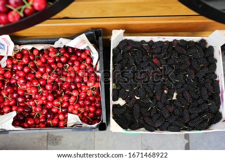 Cherry and mulberry in containers on a counter at a vegetable market in Turkey, fresh berries, street bazaar