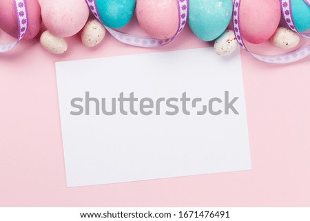 Easter greeting card with colorful easter eggs on pink background. Top view flat lay with space for your greetings