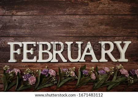 February alphabet letters with flower decoration on wooden background