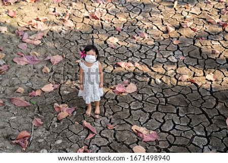 Asian girl standing at dry cracked lake, global warming concept.