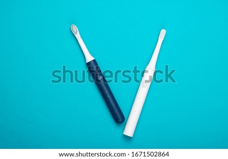 Two Modern electric toothbrushes on blue background. Top view. Teeth care. Minimalism