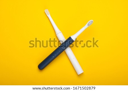 Two Modern electric toothbrushes on yellow background. Top view. Teeth care. Minimalism