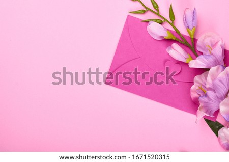 Envelope and flowers on pink background composition. Flat lay photo.