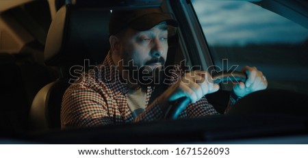 Medium shot of a sleepy man slapping himself while driving his car at night Royalty-Free Stock Photo #1671526093