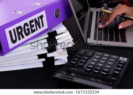 Urgent Situation Necessary Imperative Important Concept. A business woman is surrounded by large bundles of documents. Above is a purple folder with the words URGENT.