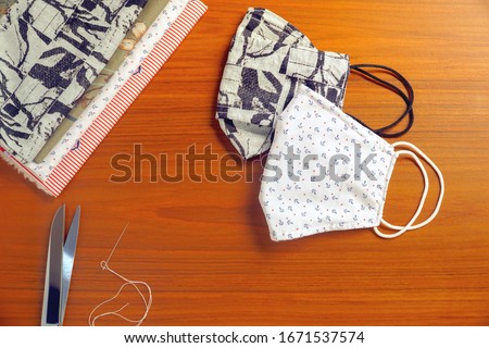 Beautiful 2 style of DIY cotton face mask, scissor and needle on wood table. Protect dust, pollution (PM2.5), Virus, Bacteria, Covid-19. Handicraft, Handmade concept. Copy space for any text design. Royalty-Free Stock Photo #1671537574