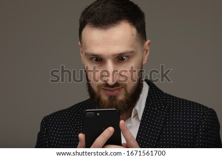 Young man texting message on smart phone isolated on grey background.