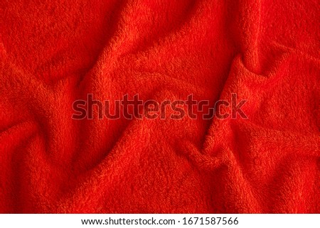 Textured red pile fabric with pleats. Background.
