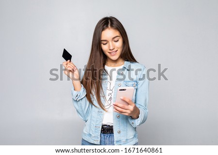 Portrait of a smiling young casual brunette woman holding credit card isolated over white background