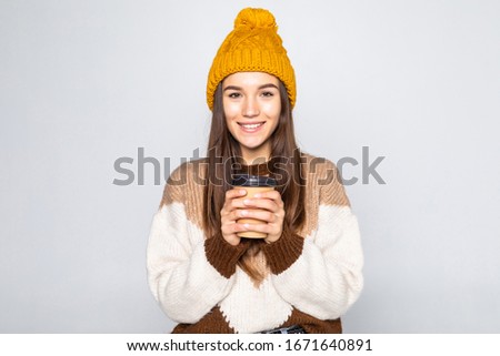 Cheerful woman, woman in a sweater and a hat with coffee in her hands posing on a white background