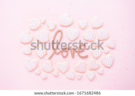 Flat lay. Heart shaped sugar cookies decorated with royal icing for Valentine's Day on a pink background.