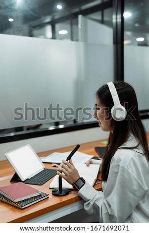 Black long hair podcaster girl in white shirt wearing white headphone telling the fun story while broadcast.