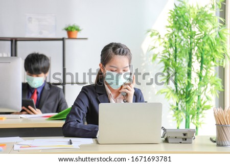 Business workers wearing medical face mask for social distancing in new normal situation for virus prevention in the office reopen and answering phone call from customer during the coronavirus disease Royalty-Free Stock Photo #1671693781