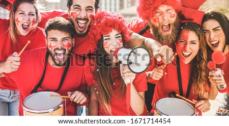 Red sport fans screaming while supporting their team out of the stadium - Football supporters having fun at competion event - Champions and winning concept - Focus on center girl face Royalty-Free Stock Photo #1671714454
