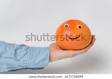 grapefruit-smiley with funny face rests on palm on white background