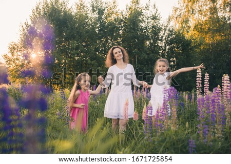 Mom and two daughters in dresses in a field with flowers