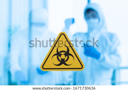 Blur photo of doctor team in sterile dress  working together in clean room with dangerous warning tag for biological  hazard sign on clear  glass door.