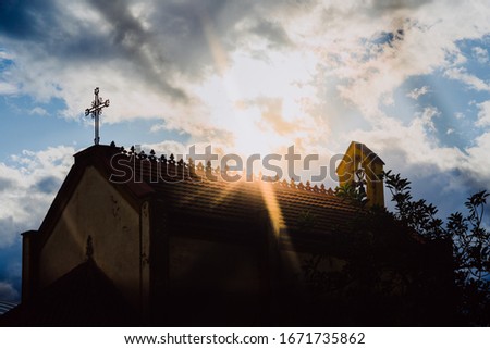 Silhouette of a church with the sun behind between the clouds, low key image.