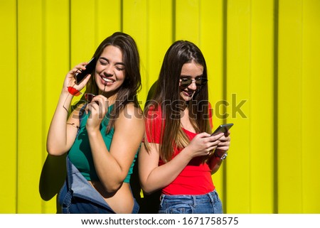 Young women with happy face  against green wall listen music on headphones and have fun