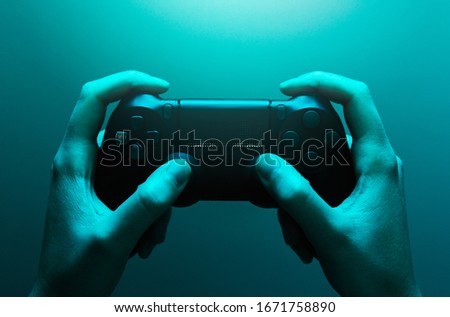 Stock photo of hands holding a black gamepad with a blue light