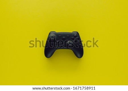 Stock photo of a black gamepad in the middle of a green background