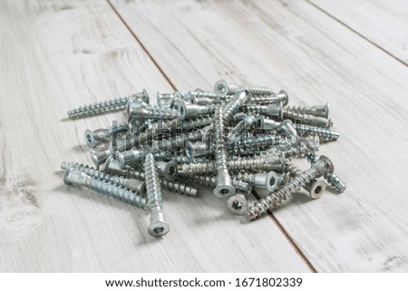 Group of Screw bolts for furniture assembling on wooden background. Stock photo.