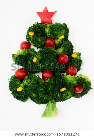Christmas edible tree made from broccoli, tomato and corn on a white plate. Christmas card with gifts and dietary salad. Royalty-Free Stock Photo #1671811276