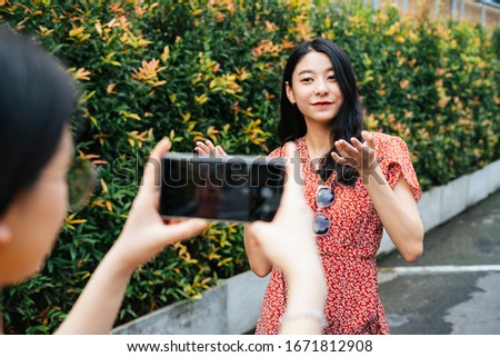 Beautiful asian thai woman vlogging with friend holding camera. Food blogger. Taking video and picture with camera on smartphone. Copy space on telephone.
